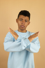 Vertical image of a dark skinned Latino teenager wearing a pastel blue sweatshirt, with an angry...