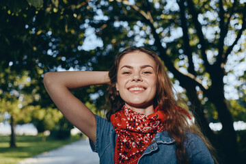 Naklejka premium lifestyle woman in modern boho-western denim street style smiling outdoors with film color effect under bright sunlight and green trees background