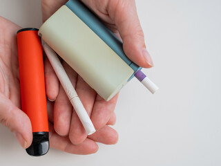 Woman holding regular, electronic cigarette and disposable vape on white background. Tobacco...