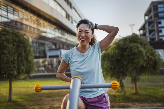 Mature japanese woman exercise on an stationary bike in outdoor gym