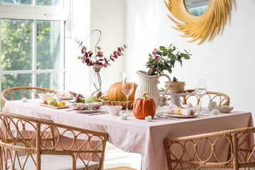 Autumn table setting decorated for Thanksgiving Day with pumpkins and eucalyptus branches in light dining room