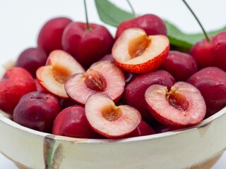 Close-up of fresh red cherries in a bowl, some halved to reveal juicy interiors