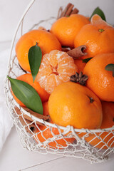 Basket of sweet mandarins with cinnamon and star anise on white wooden table