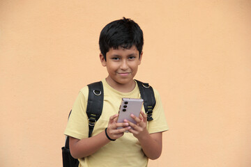A 10-year-old Latino boy uses his cell phone to play video games, make video calls, send messages,...