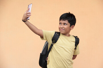 A 10-year-old Latino boy uses his cell phone to play video games, make video calls, send messages,...