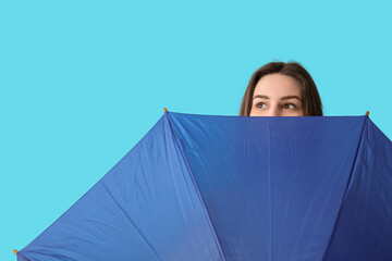 Young woman with opened umbrella on blue background