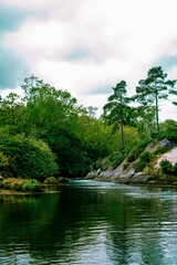 Obraz premium Vertical shot of waterscape with vibrant greenery and river in Ireland, Blue Pool Park in Glengarriff