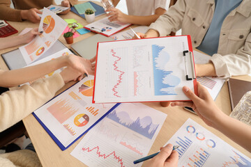 Young business people with diagrams working on marketing plan in office, closeup