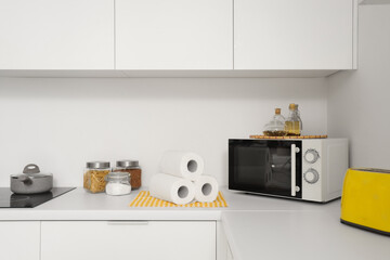 Rolls of paper towels with food and microwave oven on counter in kitchen