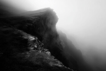 Dramatic dark cliff edge shrouded in thick fog