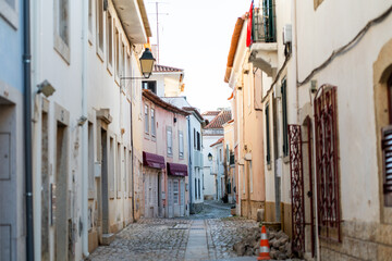 Peaceful cobblestone street in Cascais showcases traditional architecture with colorful facades....