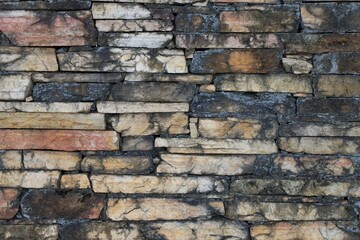 A wall made of stone with a lot of cracks and dirt