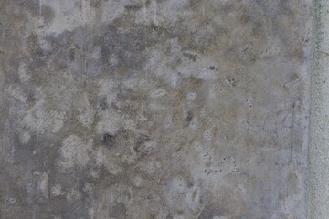 A grey concrete wall with a few cracks and holes