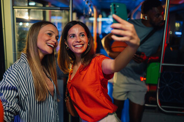 Two cheerful women taking a selfie on a moving bus with a basketball player