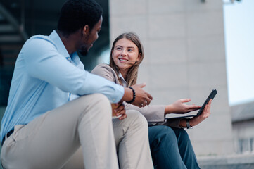 Business colleagues discussing work on laptop outdoors
