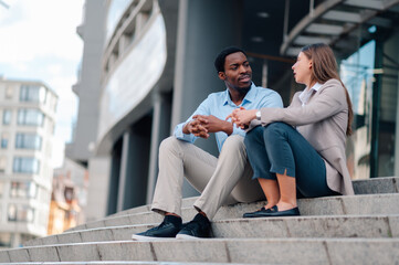 Business partners discussing new project sitting on stairs in urban environment