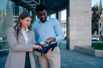 Business colleagues collaborating on laptop outside office building