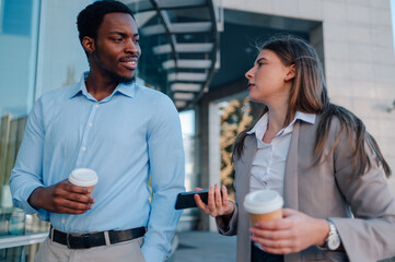 Businesspeople discussing work while walking and drinking coffee