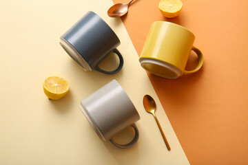 Ceramic cups with teaspoons and lemon on color background top view