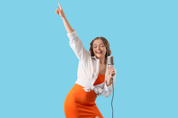 Happy young woman with microphone singing karaoke on blue background