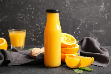 Bottle of fresh orange juice with mint on black background