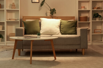 Interior of stylish living room with grey sofa and coffee table at evening