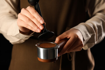 Female barista holding portafilter with coffee powder, closeup