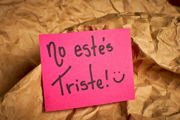 Encouraging Spanish message Don't be sad handwritten on paper