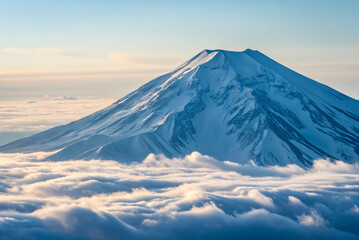 Majestic snow capped mountain peak emerges from a sea of clouds at sunrise