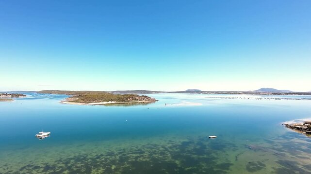 Golden Hour Pass Above Working Oyster Lease and Harvest Boat, Cinematic Aerial Reveal of Pristine Aquaculture Waters, South Australia, Pull‑Away Shot Framing Oyster Baskets Against Coastal Wetlands