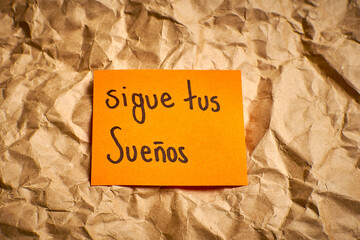 Spanish inspirational message Follow your dreams handwritten on vibrant paper 