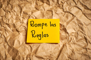 Spanish motivational phrase Break the rules handwritten on paper with colorful background