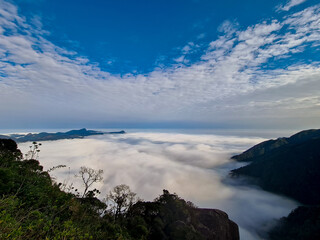 High mountains emerging from a layer of clouds with the appearance of a rough sea
