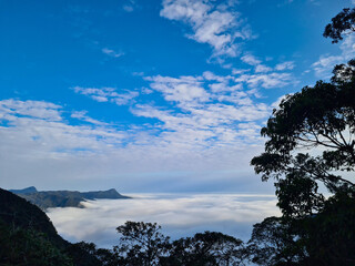 High mountains emerging from a layer of clouds with the appearance of a rough sea