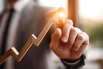 Businessman pointing at wooden upward arrow graph symbolizing business growth, career success, financial achievement and market progress
