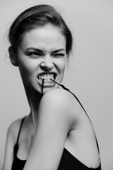 Fierce young woman with an intense expression, playfully biting on a hair tie, showcasing...