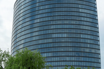Modern skyscraper with glass facade in urban setting. The interplay of nature and architecture in a...