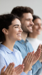Smiling people clapping hands in row showing appreciation and happiness in bright indoor setting