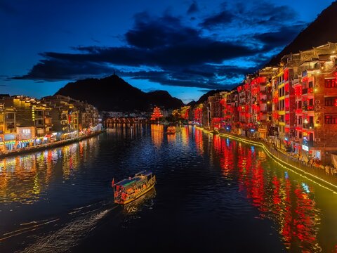 Wu Yang River night view with beautiful lights on around Zhen Yuan historical town on both sides of the river, Gui Zhou Province, China. A touring boat comes into the view.