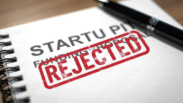 Close Up of Rejected Stamp on Startup Pitch Funding Proposal Notebook on Wood Table