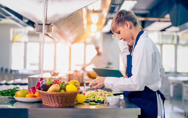 Young chef cooking at restaurant kitchen.