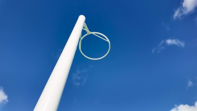 A modern outdoor netball hoop with white pole and circular ring set against a vivid blue sky. Public sports infrastructure in Australian community parks and schools.
