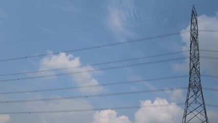 Electrical Transmission Tower Against a Blue Sky with Clouds, Steel Lattice Tower Dominating the...