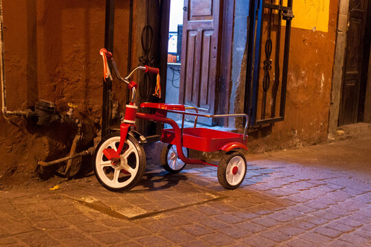 Parked Tricycle Outside Open Door at Night