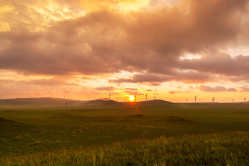 Obraz premium Wind turbines on the undulating grasslands under the sunset glow