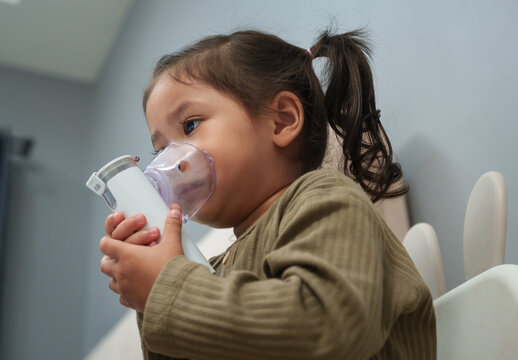 toddler girl making inhalation treatment with nebulizer at home
