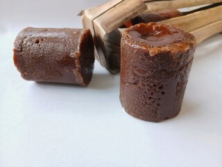 Brown sugar or palm sugar or gula Jawa wrapped in leaves  placed on White background.