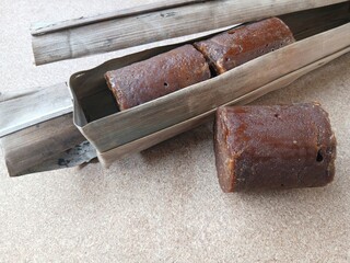 Brown sugar or palm sugar or gula Jawa  wrapped in leaves is placed on Wooden background.