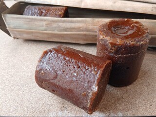 Brown sugar or palm sugar or gula Jawa  wrapped in leaves is placed on Wooden background.