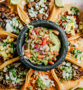 A Bowl of Guacamole and Pico Surrounded by Tacos